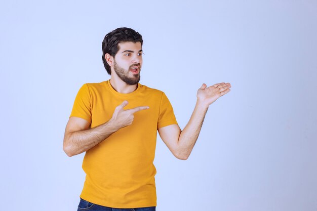 Uomo in camicia gialla che mostra qualcosa a destra.