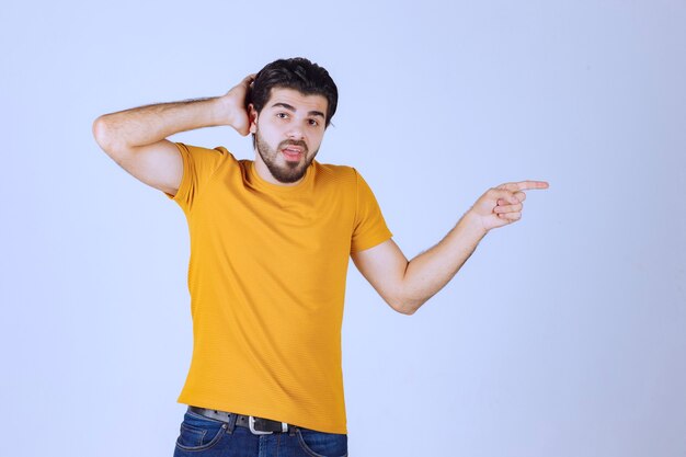 Uomo in camicia gialla che mostra qualcosa a destra.