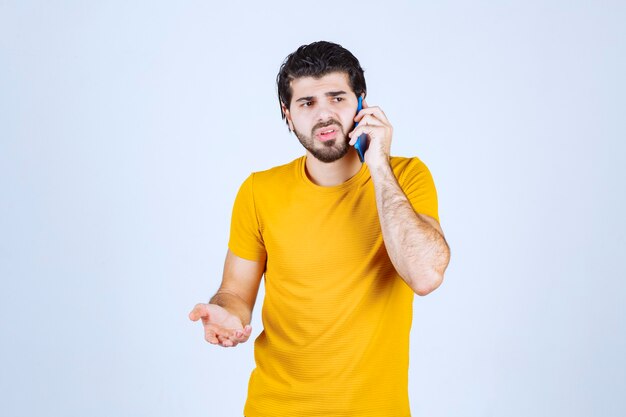 Uomo in camicia gialla che parla al telefono.