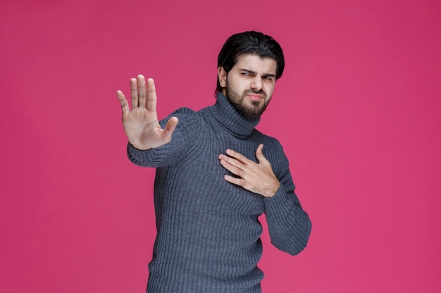 Uomo in camicia grigia spaventato da qualcosa o che rifiuta.