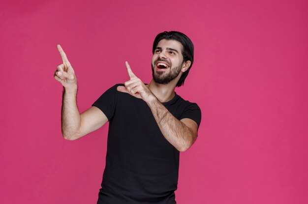 Uomo in camicia nera che indica qualcosa o che presenta qualcuno