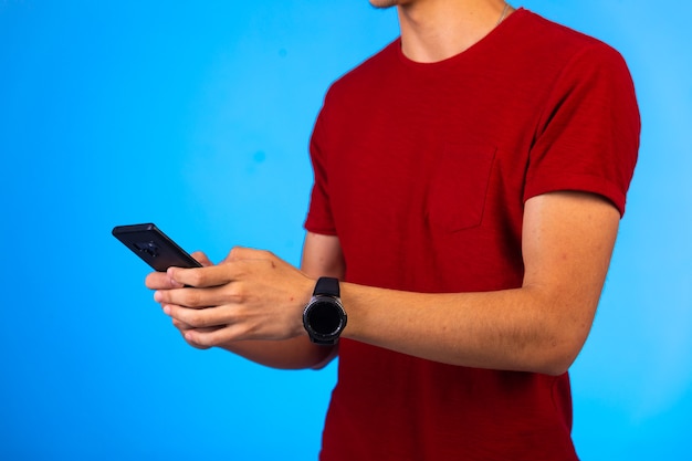 Uomo in camicia rossa che tiene e che chiacchiera su uno smartphone