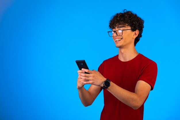 Uomo in camicia rossa prendendo selfie su uno smartphone.