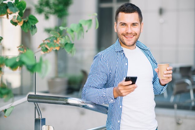 Uomo in camicia utilizzando il telefono vicino banister