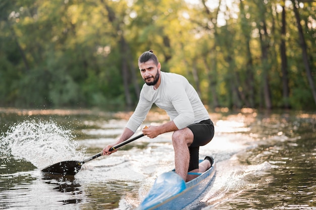 Uomo in canoa che rema a colpo pieno