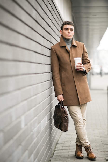 Uomo in cappotto marrone con caffè