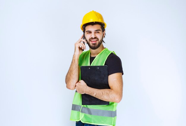 Uomo in casco giallo che parla al telefono.