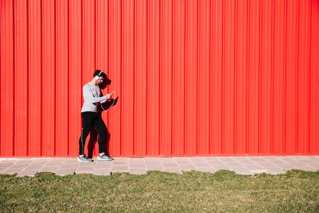 Uomo in cuffie che riposa vicino al muro rosso