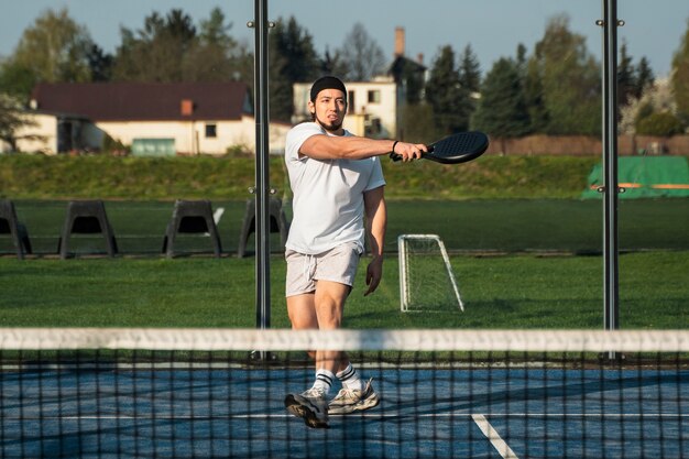 Uomo in forma a tutto campo che gioca a paddle tennis