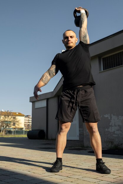 Uomo in forma a tutto campo che si esercita con il kettlebell