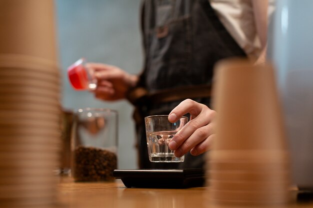 Uomo in grembiule che tiene vetro con tazze di caffè