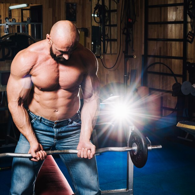 Uomo in jeans sollevamento barbell