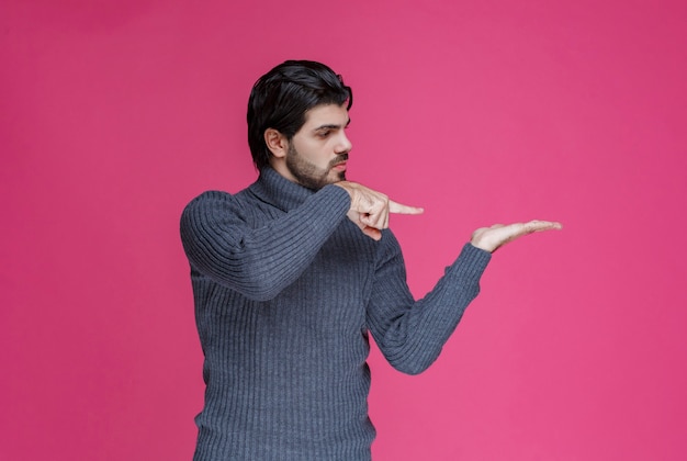 Uomo in maglione grigio che indica la sua mano.