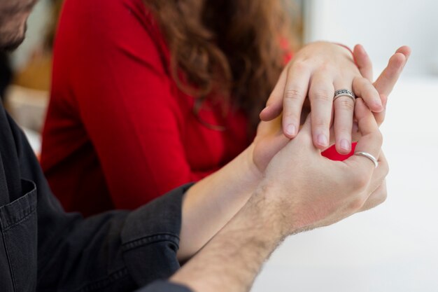 Uomo in nero che mette fede nuziale sul dito della donna