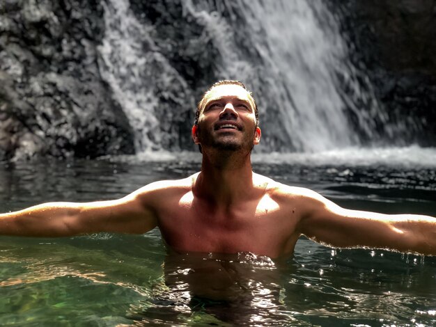 Uomo in piedi al lago con cascata