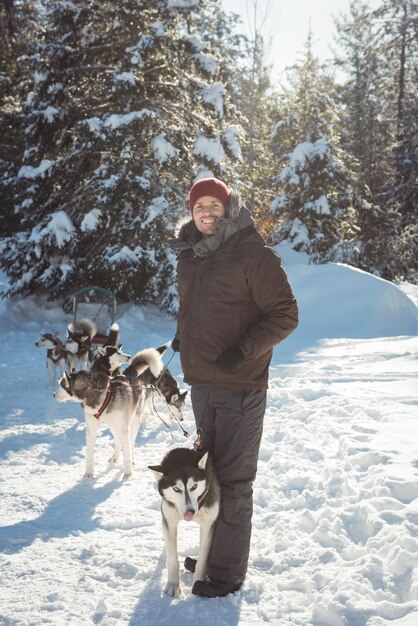 Uomo in piedi con i cani husky siberiano