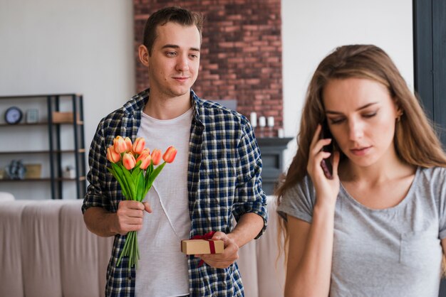 Uomo in piedi con regali dietro la donna