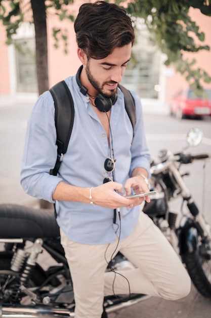 Uomo in piedi davanti alla moto tramite smartphone