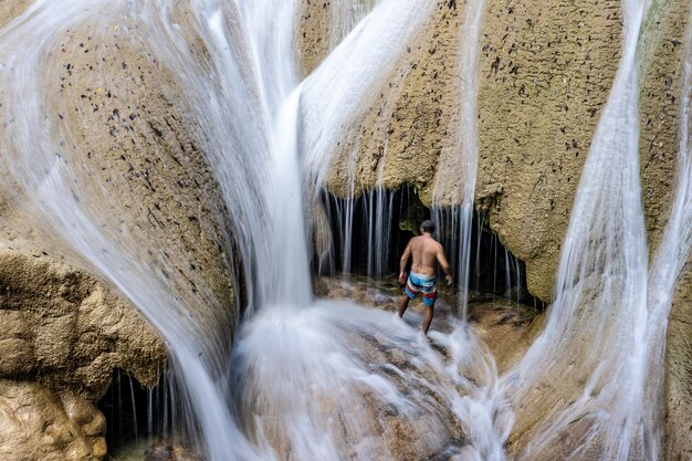 Uomo in piedi in pantaloncini corti in una grotta con acqua che scorre durante il giorno