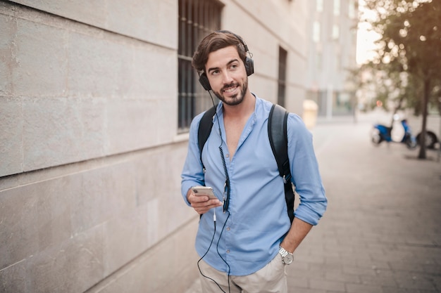 Uomo in piedi sul marciapiede ascoltando musica