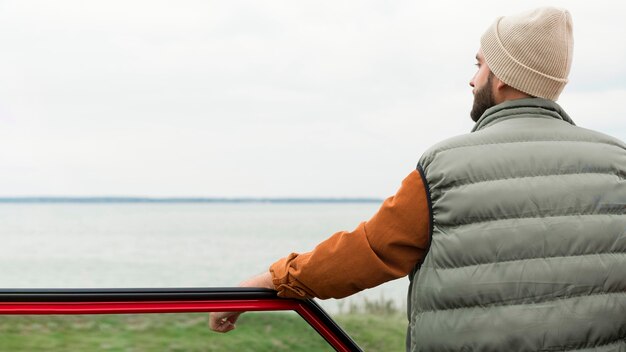 Uomo in piedi vicino all'auto in natura