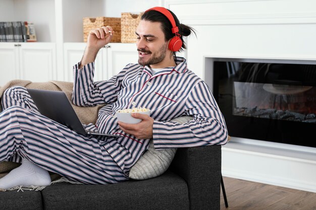 Uomo in pigiama che mangia popcorn