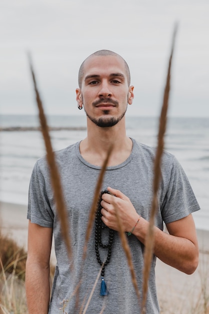 Uomo in posa all'aperto con il rosario mentre si fa yoga