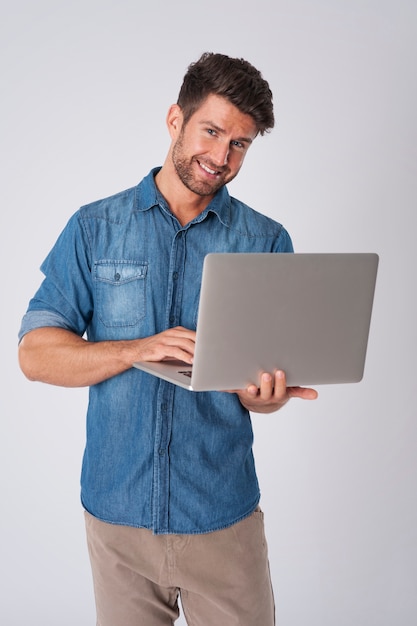 uomo in posa con camicia di jeans e laptop