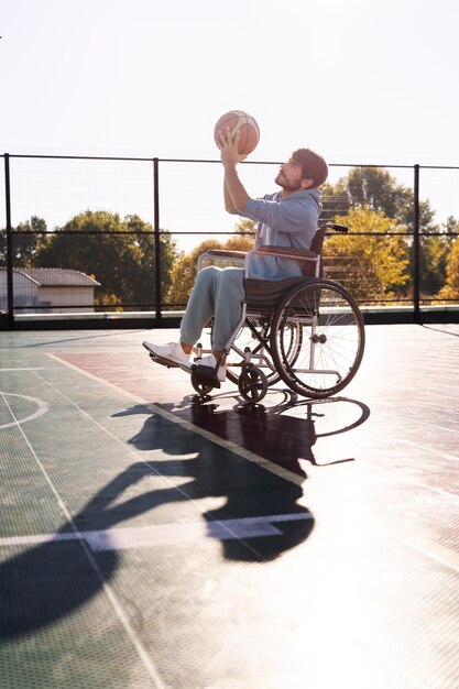 Uomo in sedia a rotelle a tutto campo che gioca a basket