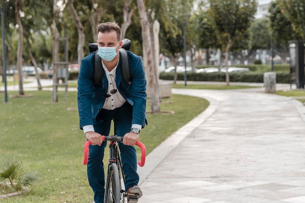 Uomo in sella a una bicicletta mentre indossa una maschera medica