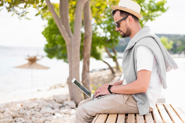 Uomo in spiaggia lavorando sul portatile