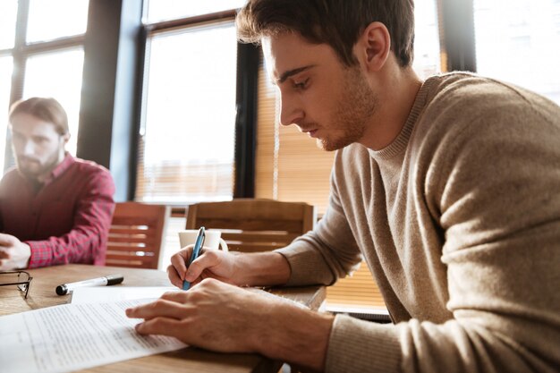 Uomo in ufficio che lavora mentre scrivendo le note al taccuino