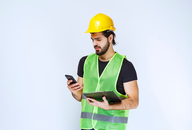 Uomo in un casco giallo che controlla i suoi messaggi.