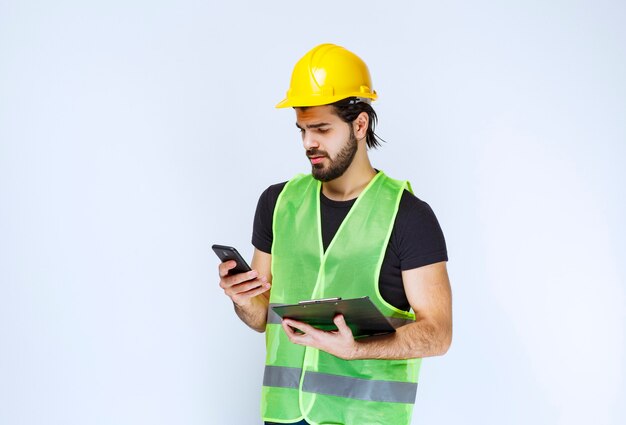 Uomo in un casco giallo che controlla i suoi messaggi.