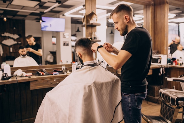 Uomo in un salone di barbiere facendo taglio di capelli e taglio della barba