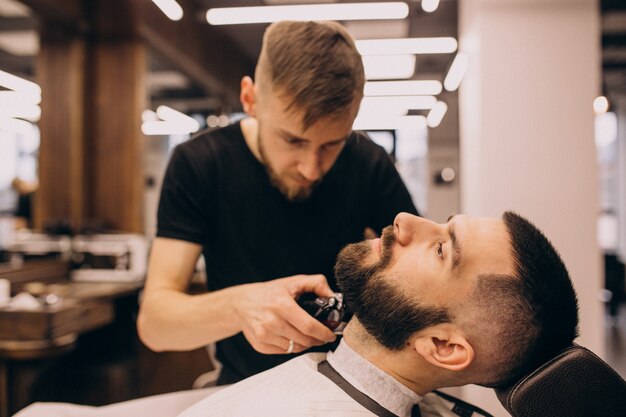 Uomo in un salone di barbiere facendo taglio di capelli e taglio della barba