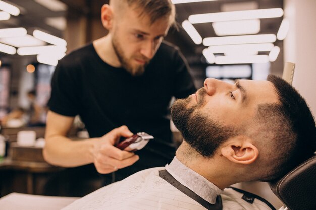 Uomo in un salone di barbiere facendo taglio di capelli e taglio della barba