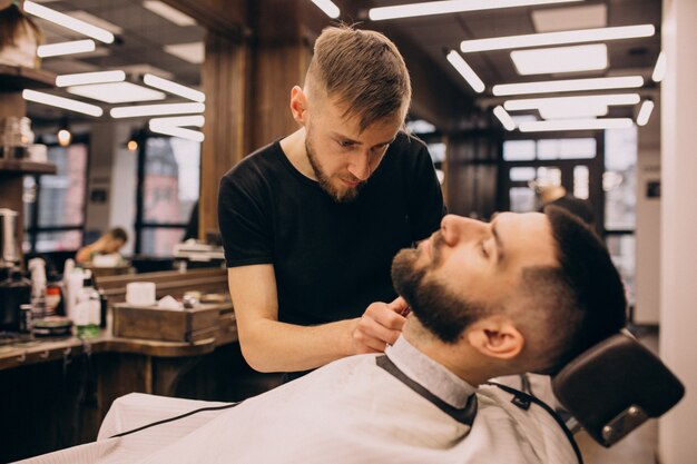 Uomo in un salone di barbiere facendo taglio di capelli e taglio della barba