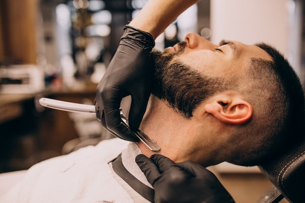 Uomo in un salone di barbiere facendo taglio di capelli e taglio della barba