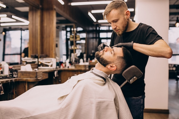 Uomo in un salone di barbiere facendo taglio di capelli e taglio della barba