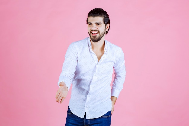 Uomo in una camicia bianca che dà la mano per scuotere.