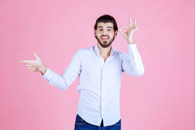 Uomo in una camicia bianca che mostra il segno positivo della mano.