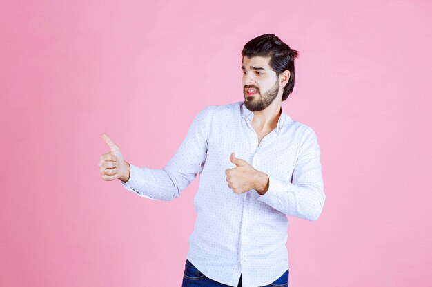 Uomo in una camicia bianca che mostra pollice in su.