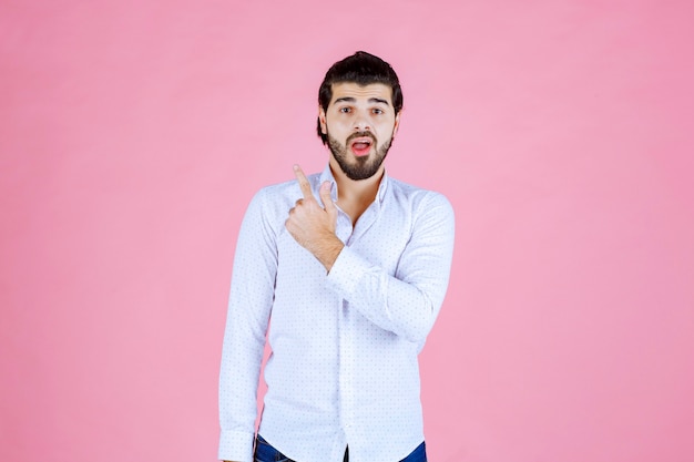 Uomo in una camicia bianca che mostra qualcosa dietro.