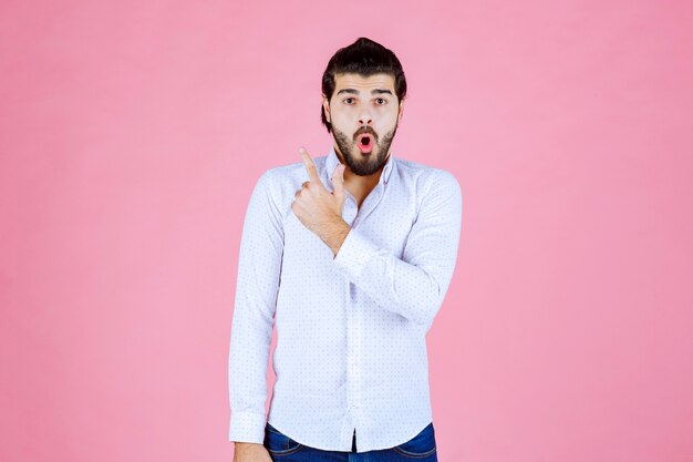 Uomo in una camicia bianca che mostra qualcosa dietro.