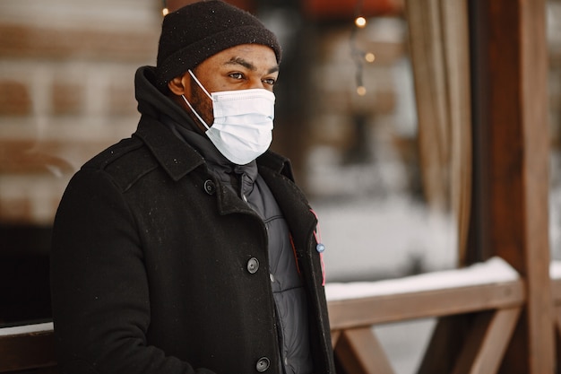 Uomo in una città invernale. Ragazzo con un cappotto nero. Uomo in una maschera medica.
