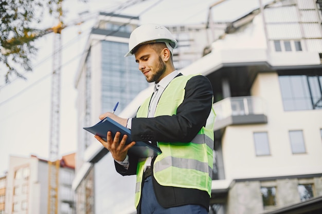 Uomo in uniforme del costruttore che tiene più vecchio. Guardando il piano dell'edificio