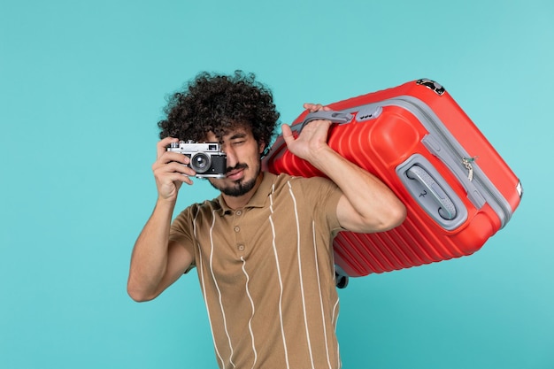 uomo in vacanza con una grande valigia che scatta foto con la fotocamera su blue