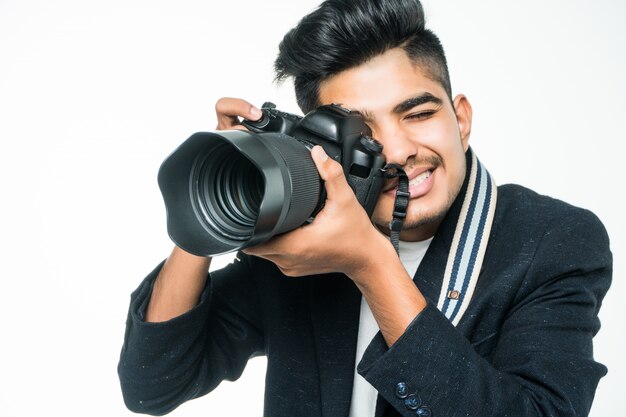 Uomo indiano del fotografo che tiene la sua macchina fotografica su un fondo bianco.