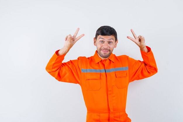 Uomo industriale in uniforme che mostra il segno di v e che sembra allegro, vista frontale.